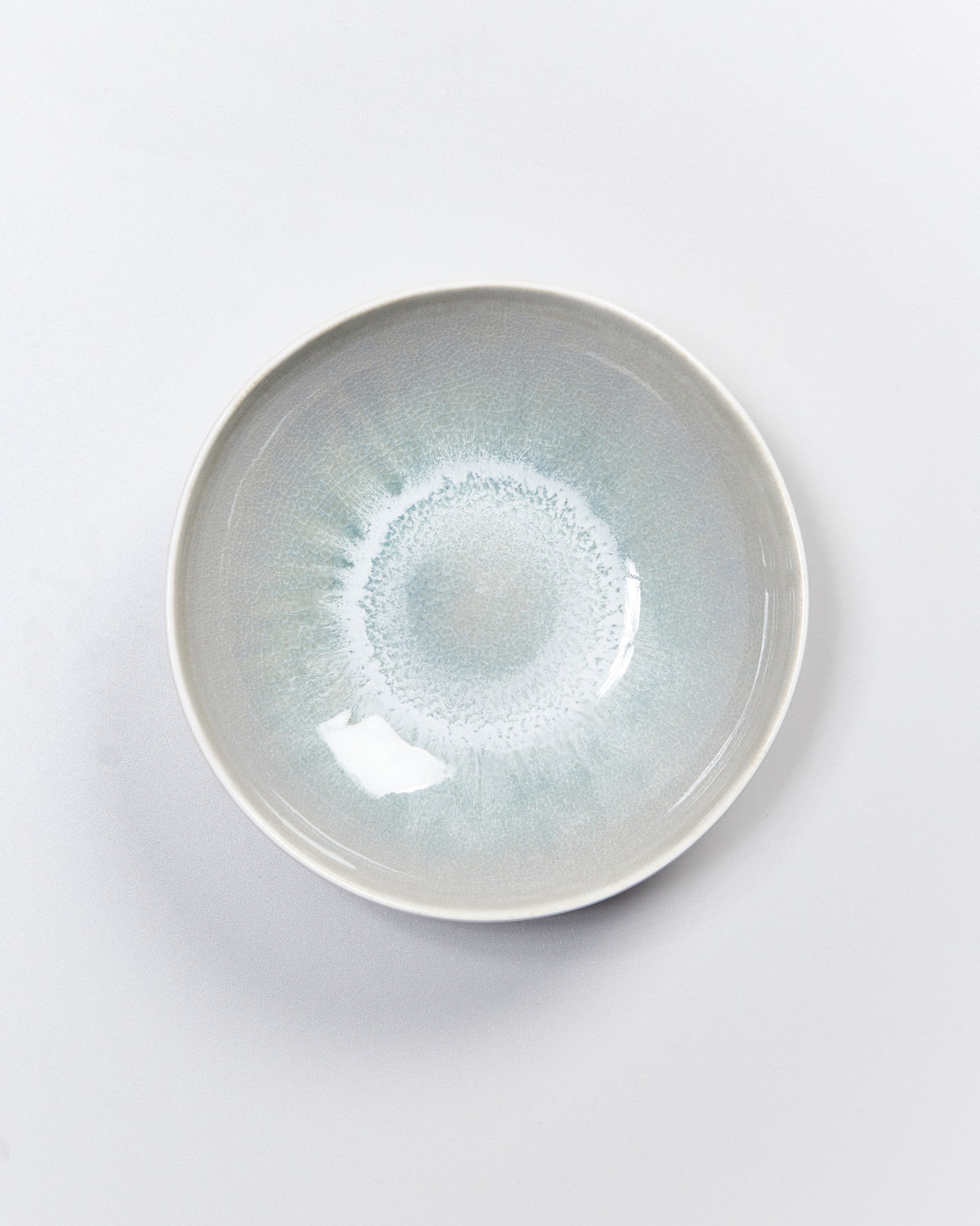 Keramikschale mit blaugrauer Glasur und kreisförmigem Muster, auf hellem Hintergrund fotografiert.