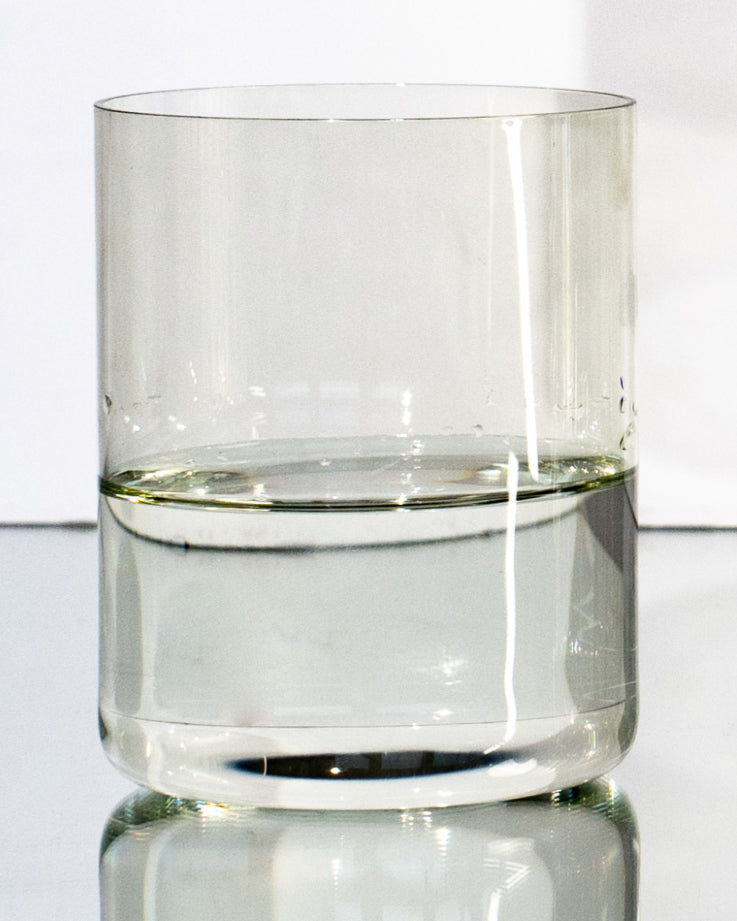 Ein Glas halb voll mit Wasser auf einem hellen Hintergrund.