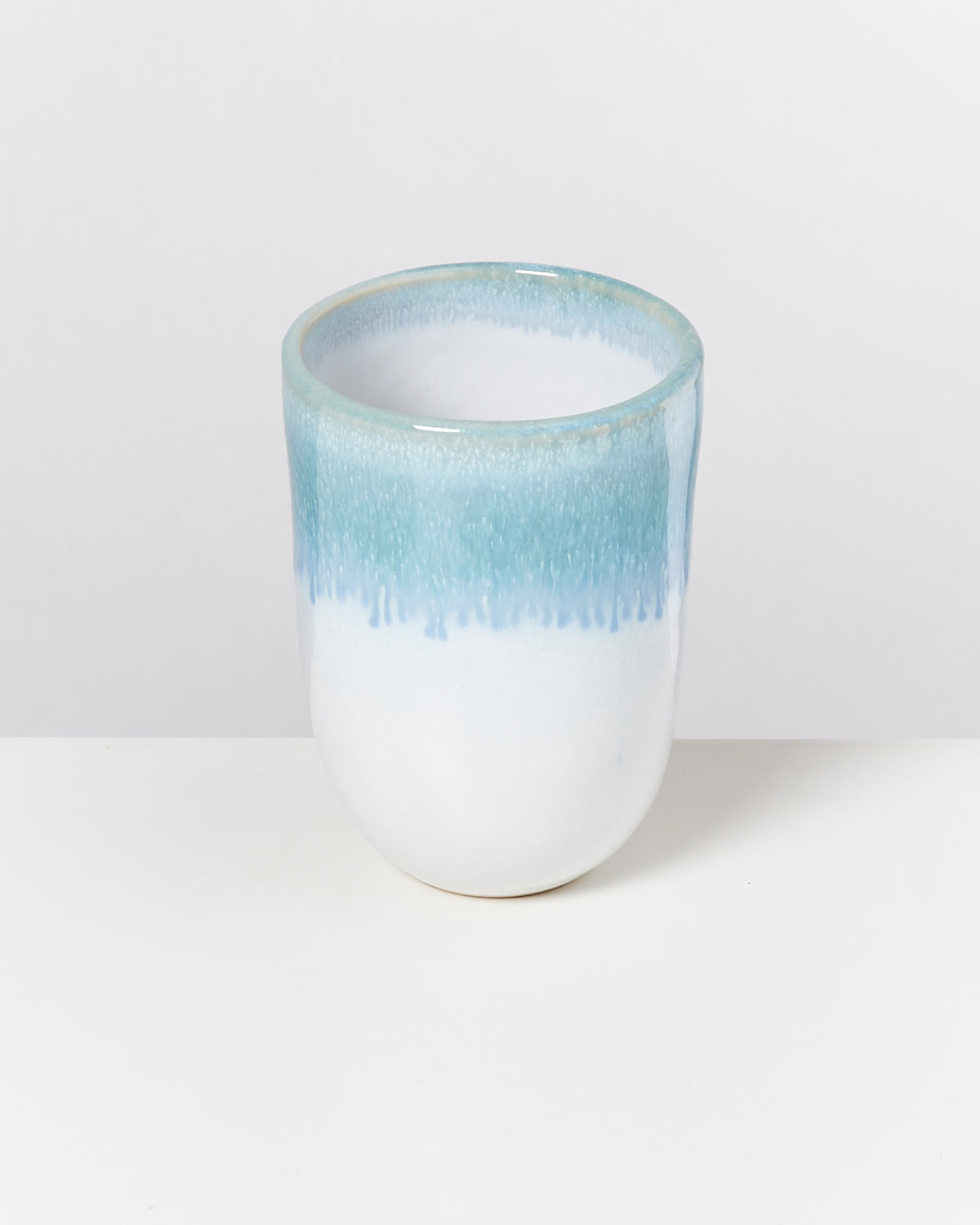 Keramikbecher mit blauem Farbverlauf von oben nach unten auf weißem Hintergrund.