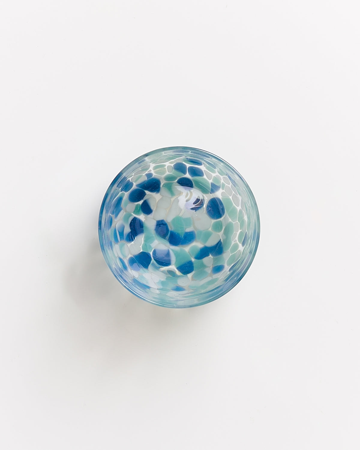 Blau-weiße, gemusterte Glasschale auf weißem Hintergrund von oben betrachtet.