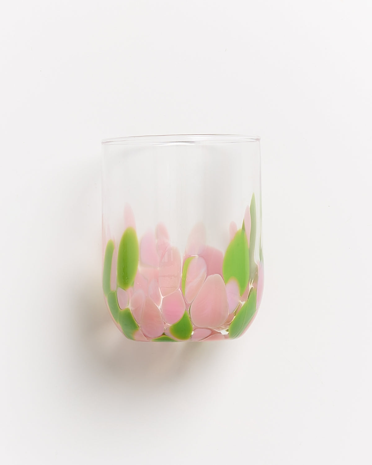 Glas mit rosa und grünen Farbmusterungen auf einer weißen Oberfläche.