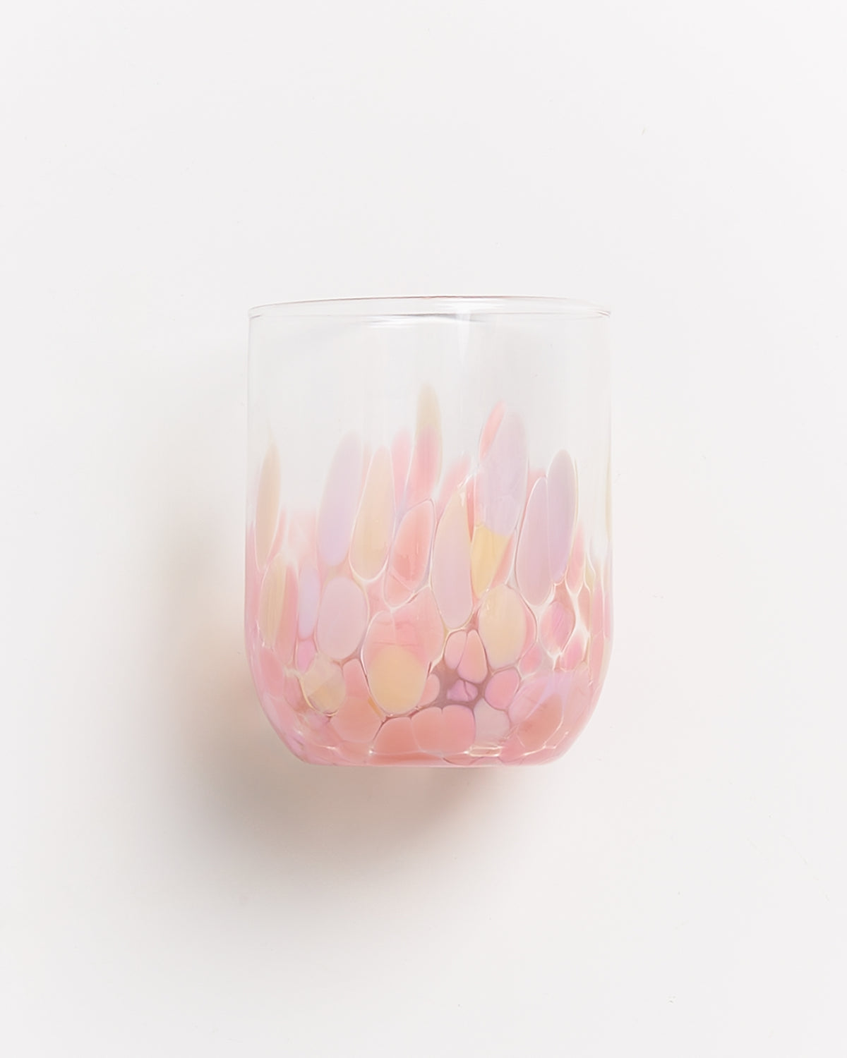 Ein farbiges Glas mit rosa, lila und gelben Mustern auf weißem Hintergrund.