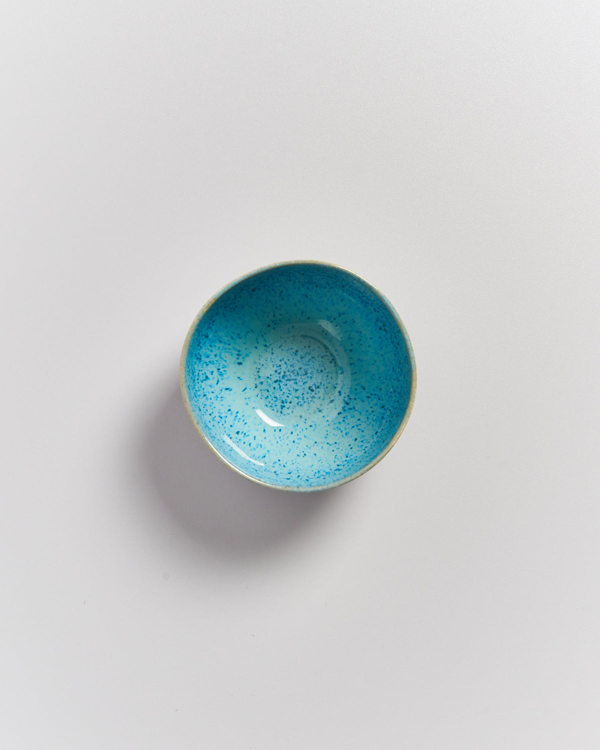 Kleine, hellblaue, gesprenkelte Schale auf weißem Hintergrund.
