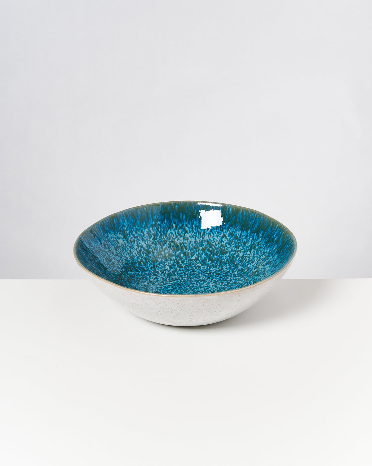 Eine Schüssel mit blau-grünem Innenbereich auf weißem Hintergrund.