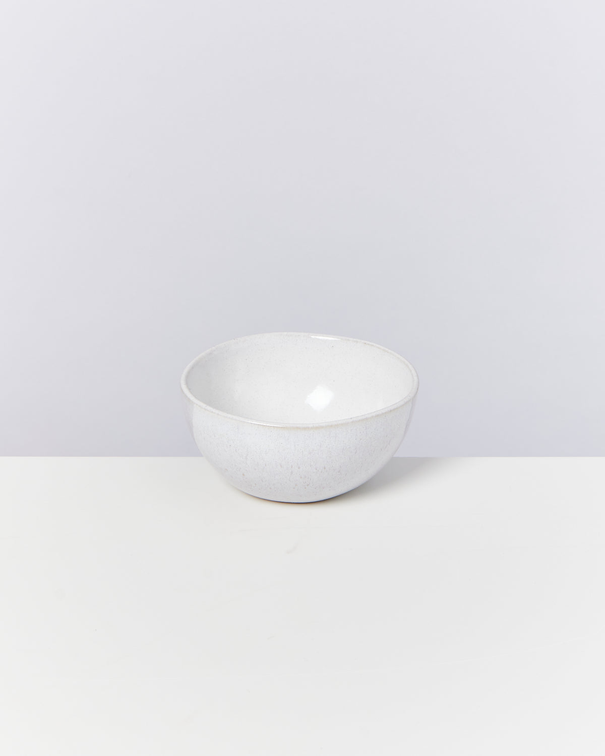 Weiße Keramikschale auf einem weißen Tisch vor einem neutralen Hintergrund.