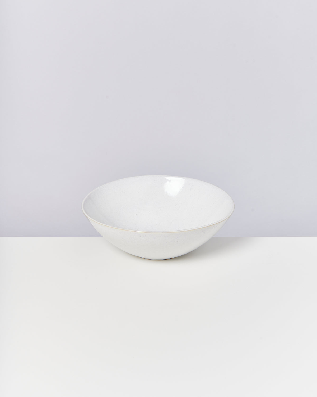 Weiße, runde Schale auf einem weißen Tisch vor einem grauen Hintergrund.
