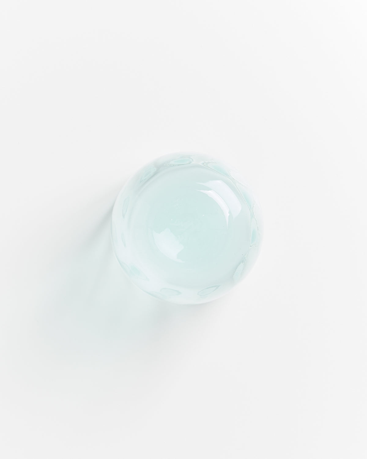 Glaskugel auf weißem Hintergrund, von oben fotografiert.