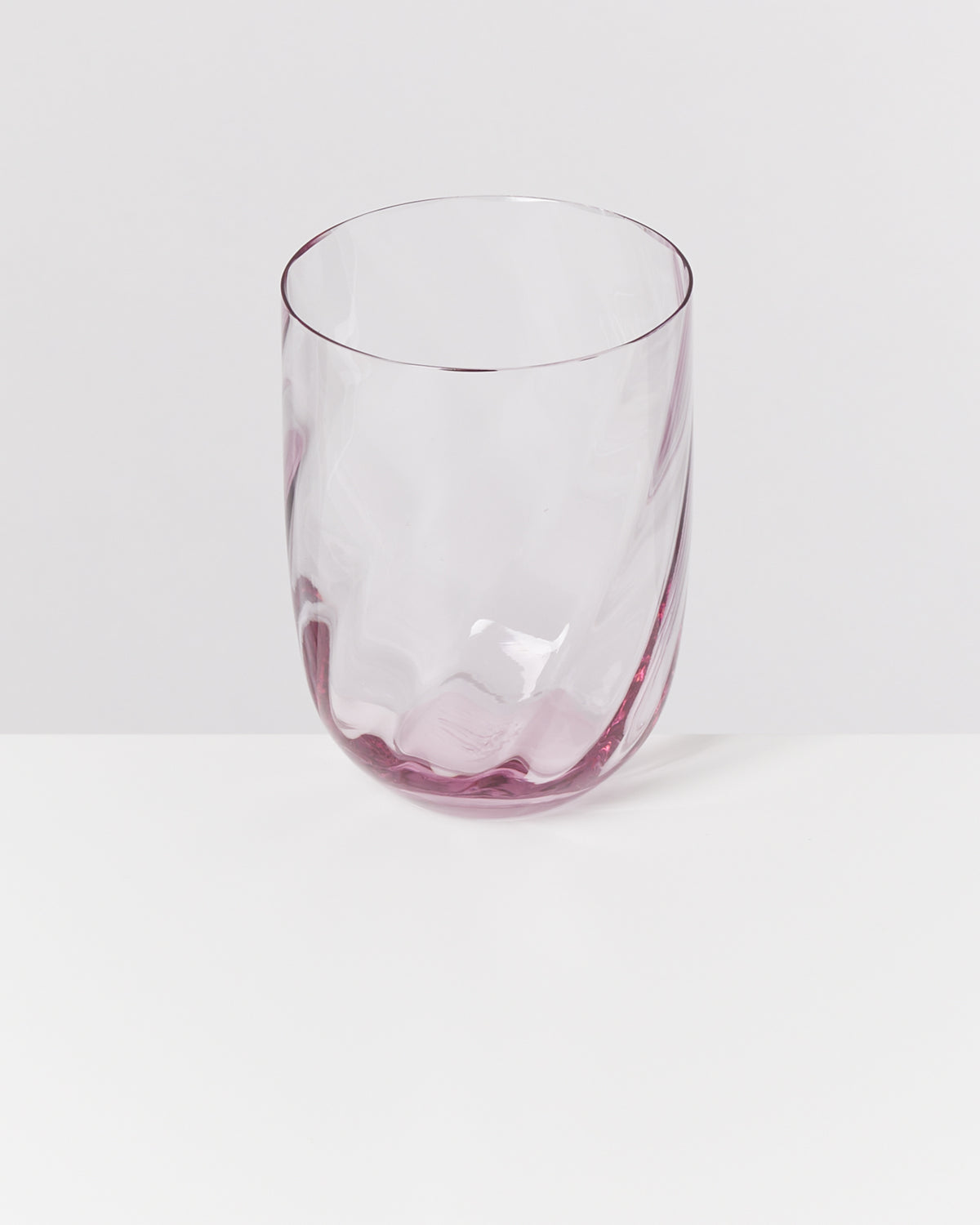 Durchsichtiges Glas mit rosafarbenem Schimmer auf einem weißen Hintergrund.