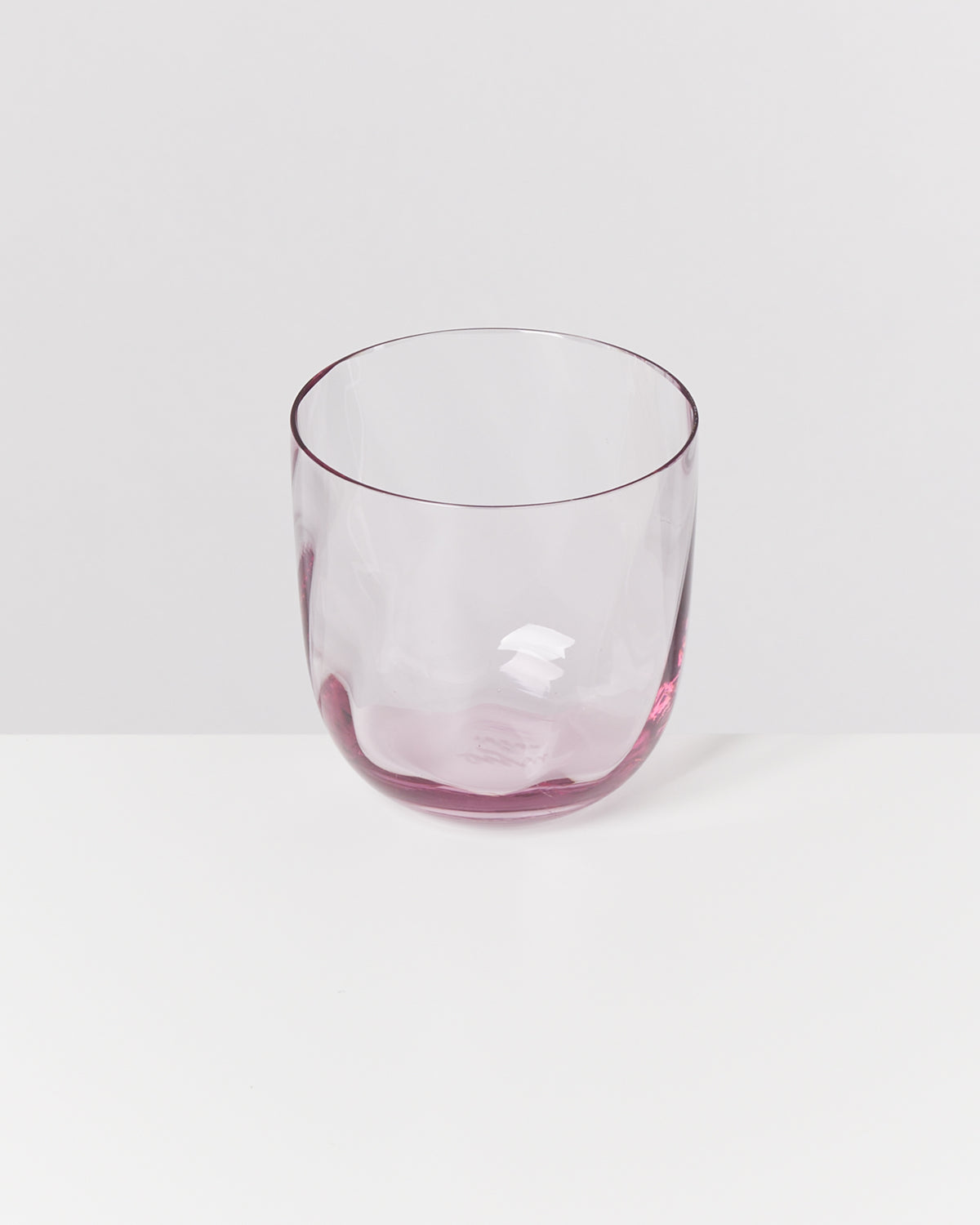 Ein transparenter rosa Trinkbecher steht auf einem weißen Hintergrund.