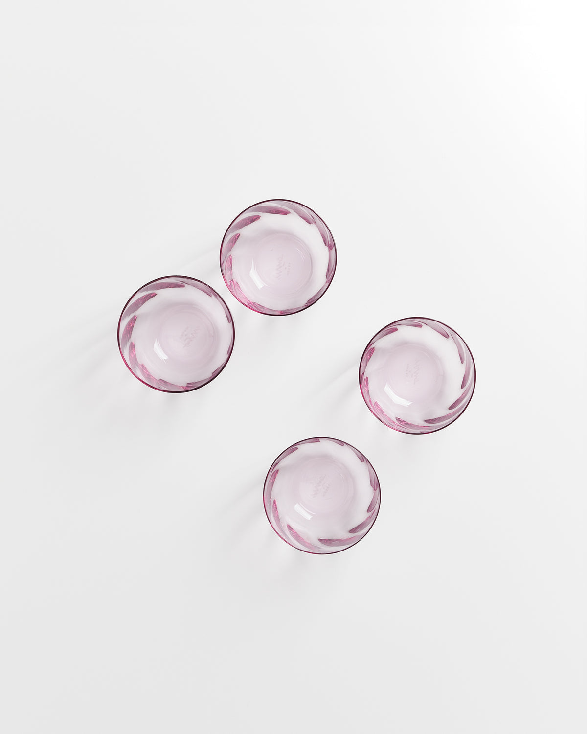 Vier rosa Glasschalen auf weißem Hintergrund, versetzt zueinander angeordnet.