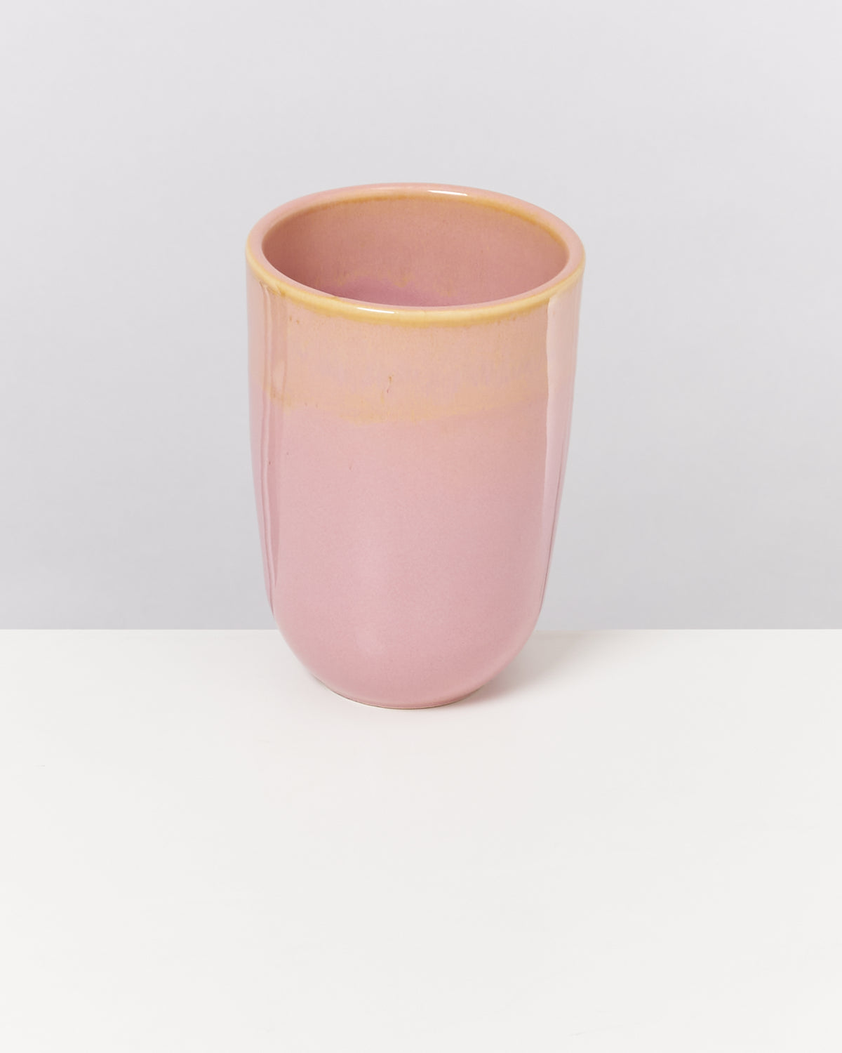 Eine rosa Keramiktasse steht auf einem weißen Hintergrund.
