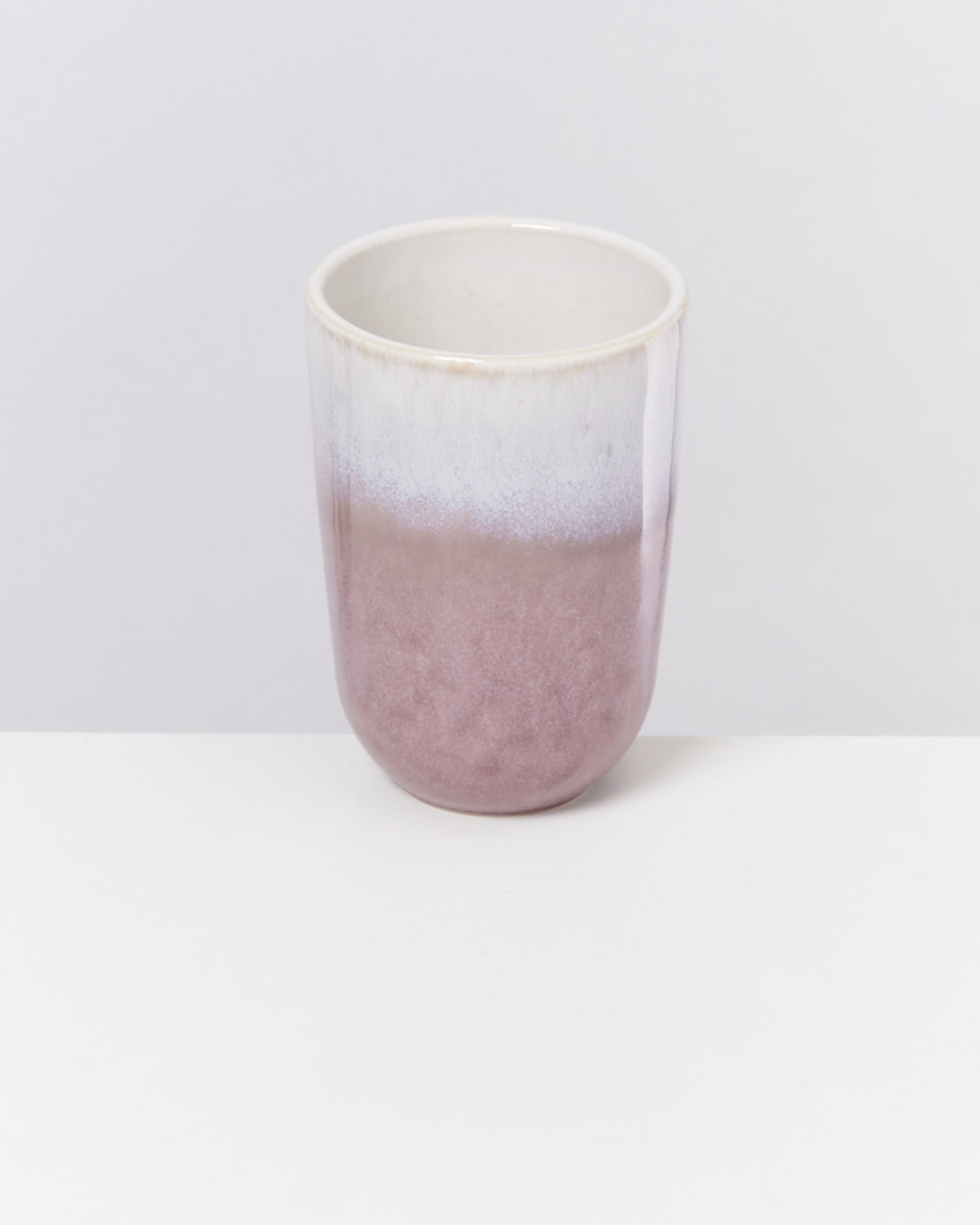 Keramikbecher mit lila-weißem Farbverlauf auf hellem Hintergrund.