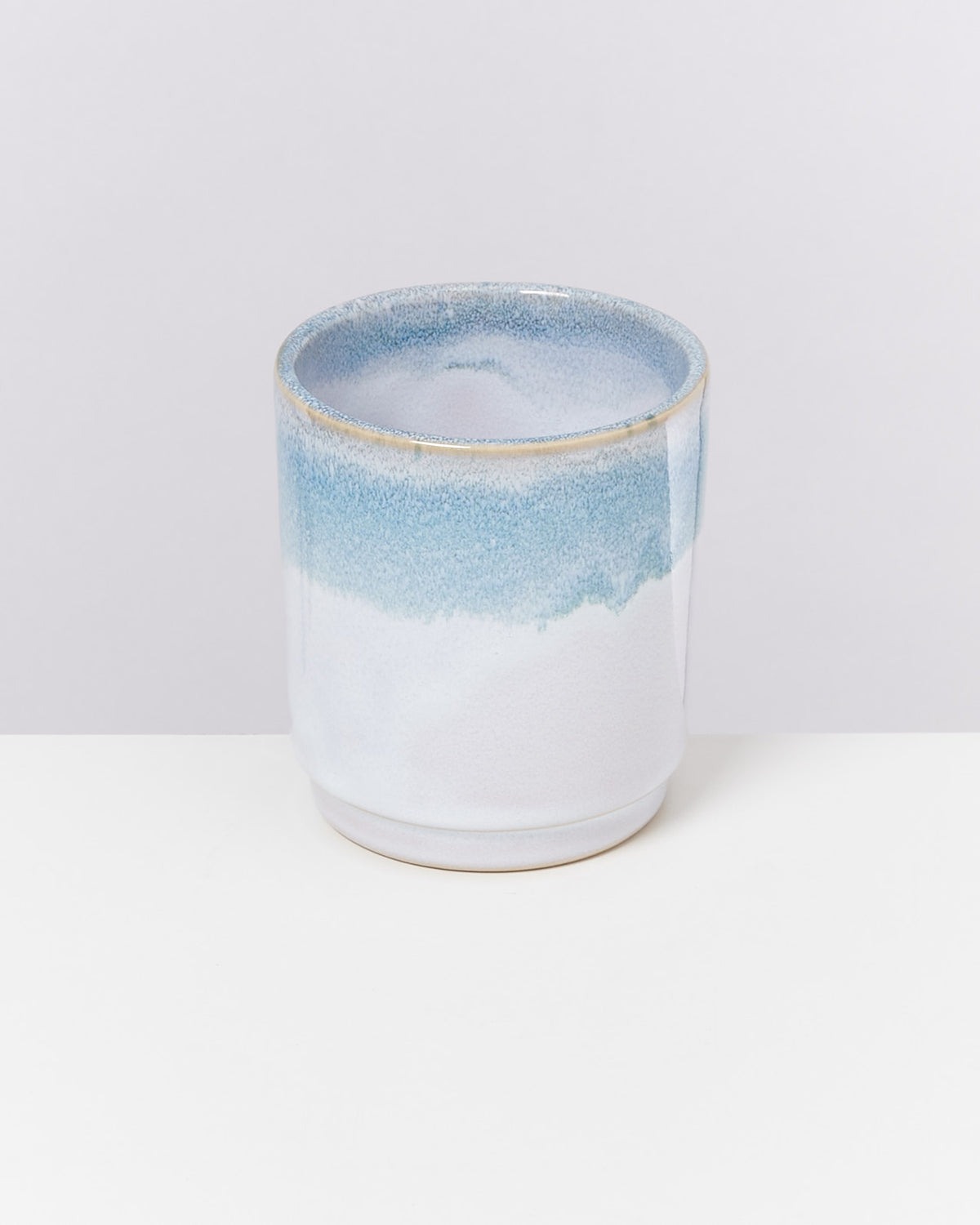 Keramikbecher mit blau-weißem Farbverlauf auf einem weißen Hintergrund.