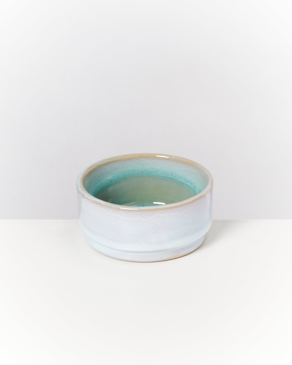 Keramikschale mit blau-grünem Farbverlauf auf einem weißen Hintergrund.