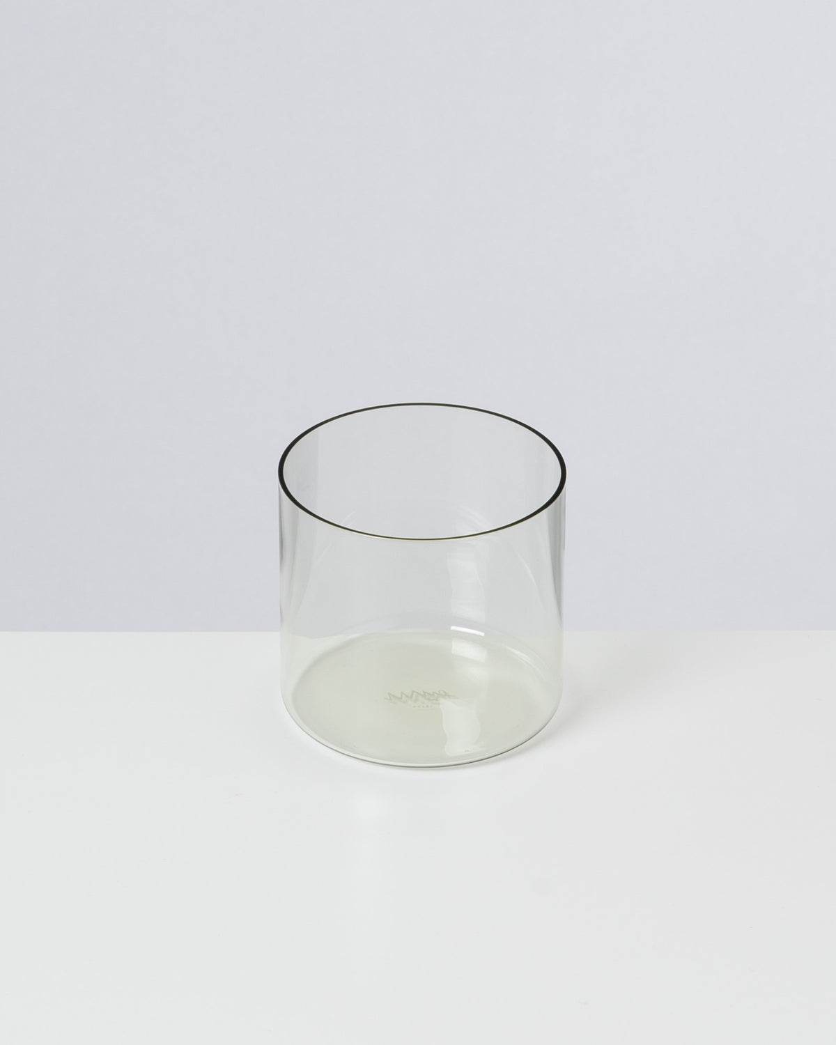 Ein transparentes, zylindrisches Glas steht auf einer weißen Oberfläche.