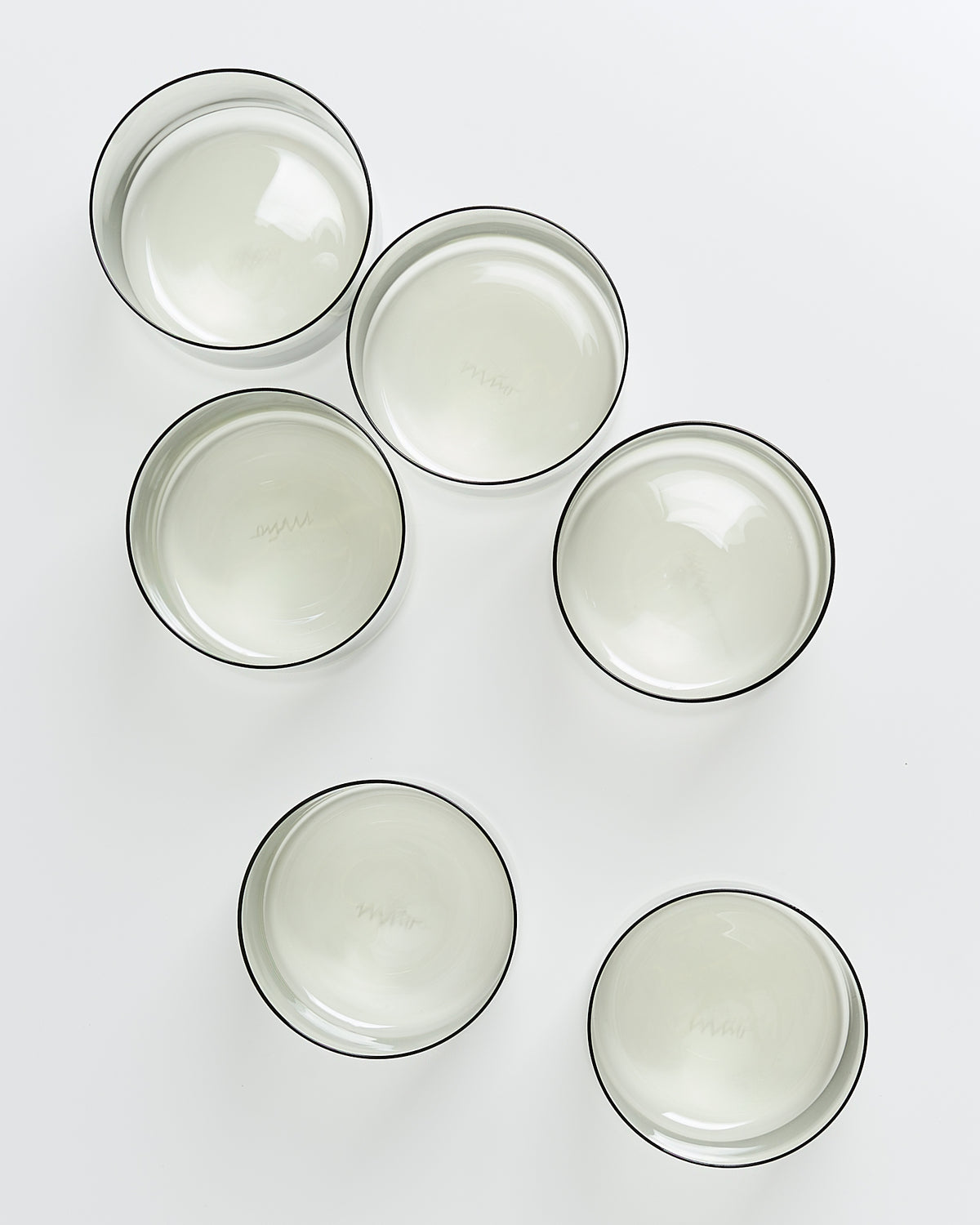 Sechs leere, durchsichtige Glasschalen mit schwarzem Rand auf weißem Hintergrund verteilt.