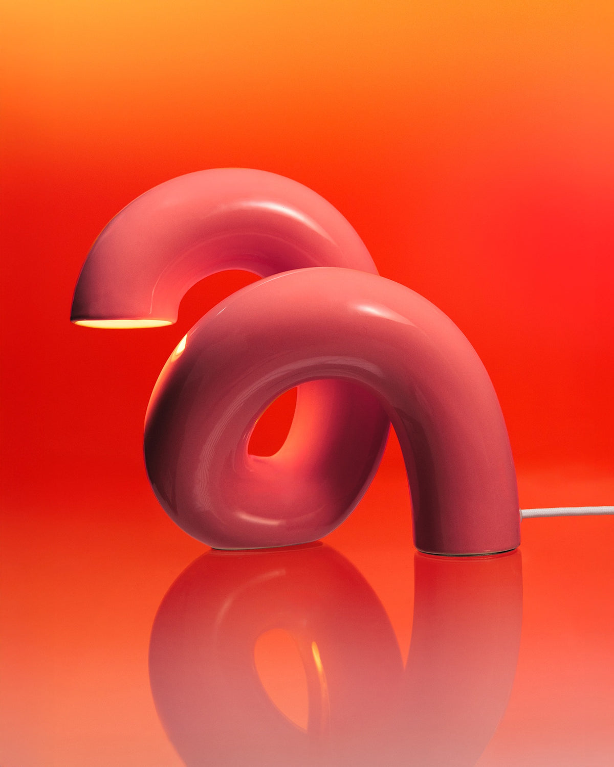 Zwei rosa, gebogene Lampen in modernem Design vor einem warmen, orangefarbenen Hintergrund.