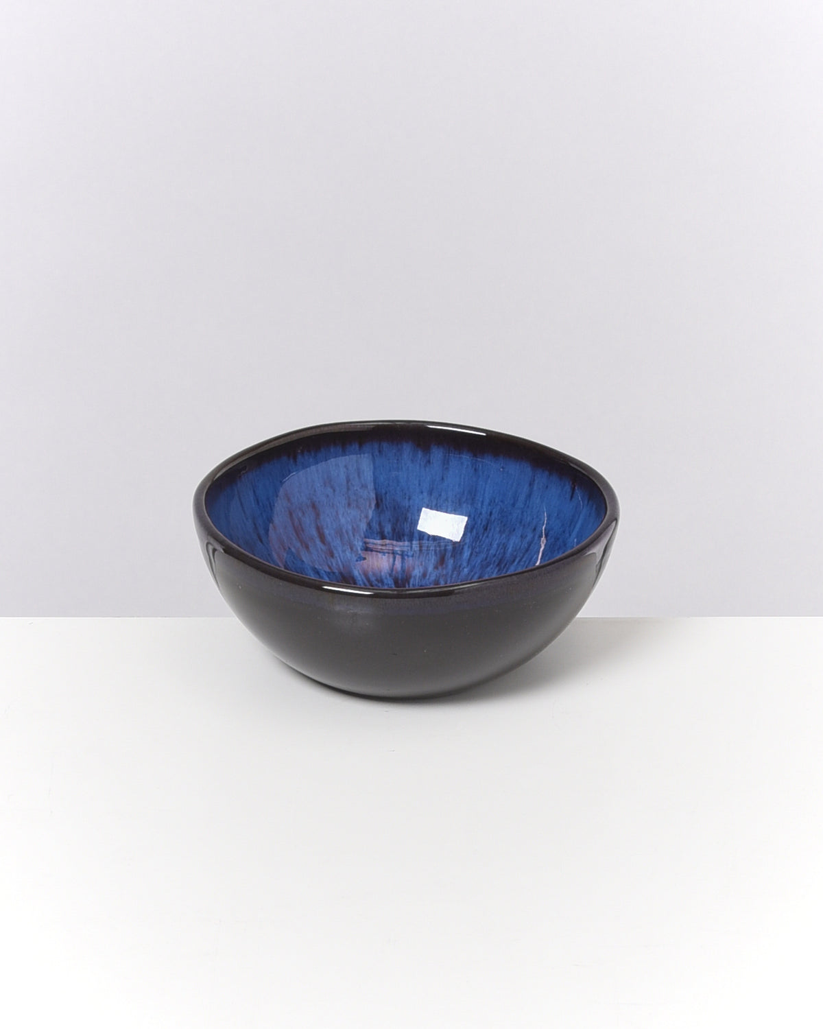 Schwarze Schüssel mit blauer Innenseite auf einem weißen Hintergrund.