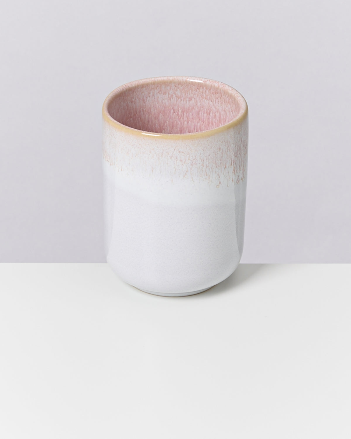Ein zylindrisches Keramikgefäß mit einem rosa Innenbereich steht auf einem weißen Hintergrund.