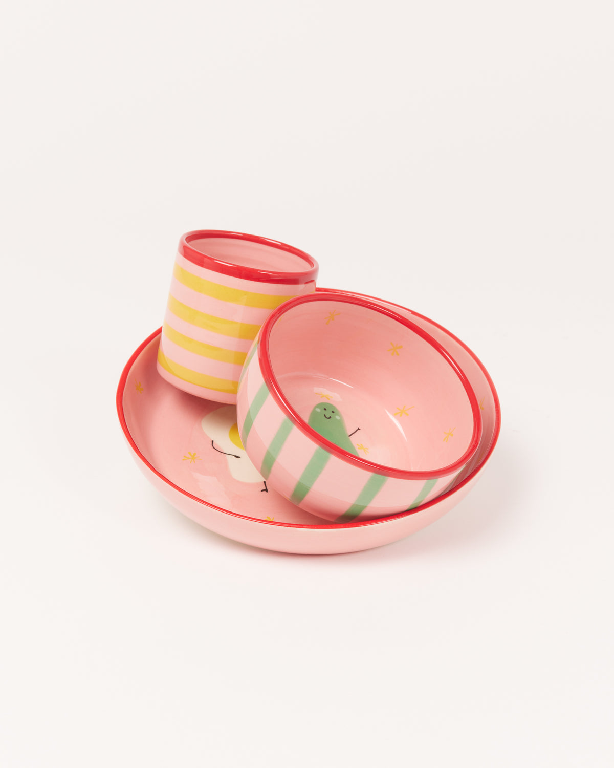 Drei bunte Schüsseln und ein Becher, rosa mit Streifen und fröhlichen Motiven, auf hellem Hintergrund.