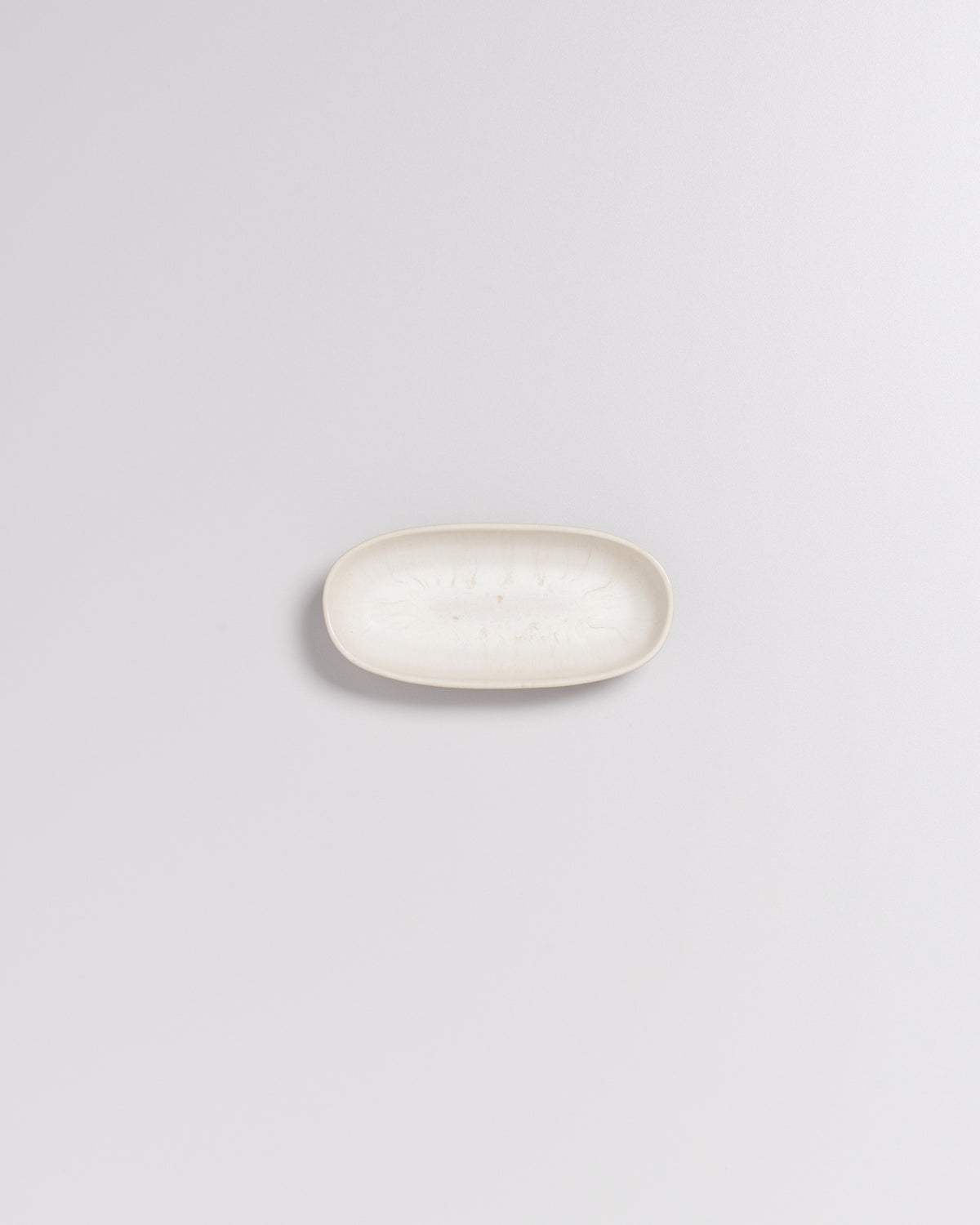 Ein ovaler, cremefarbener Ceramic-Seifenteller auf einem hellgrauen Hintergrund.