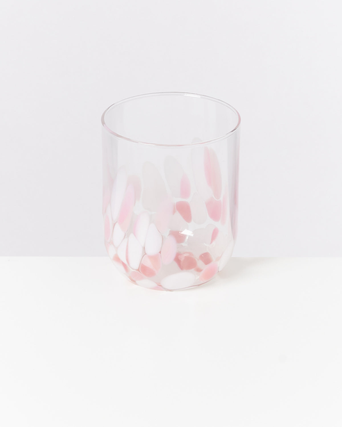 Ein Glas mit rosa und weißen Mustern steht auf weißem Hintergrund.