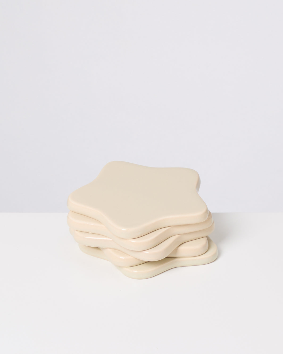 Beige, sternförmige Untersetzer auf einem weißen Hintergrund gestapelt.