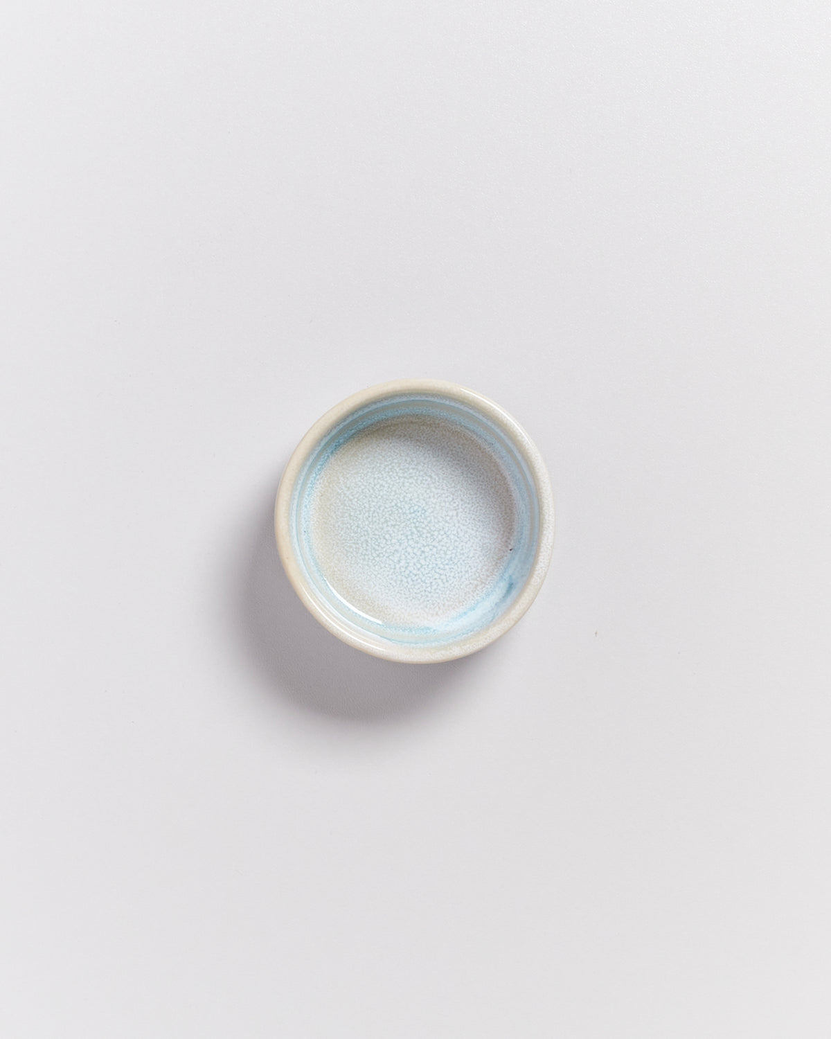 Kleine, runde, pastellblaue Schale auf einem weißen Hintergrund.