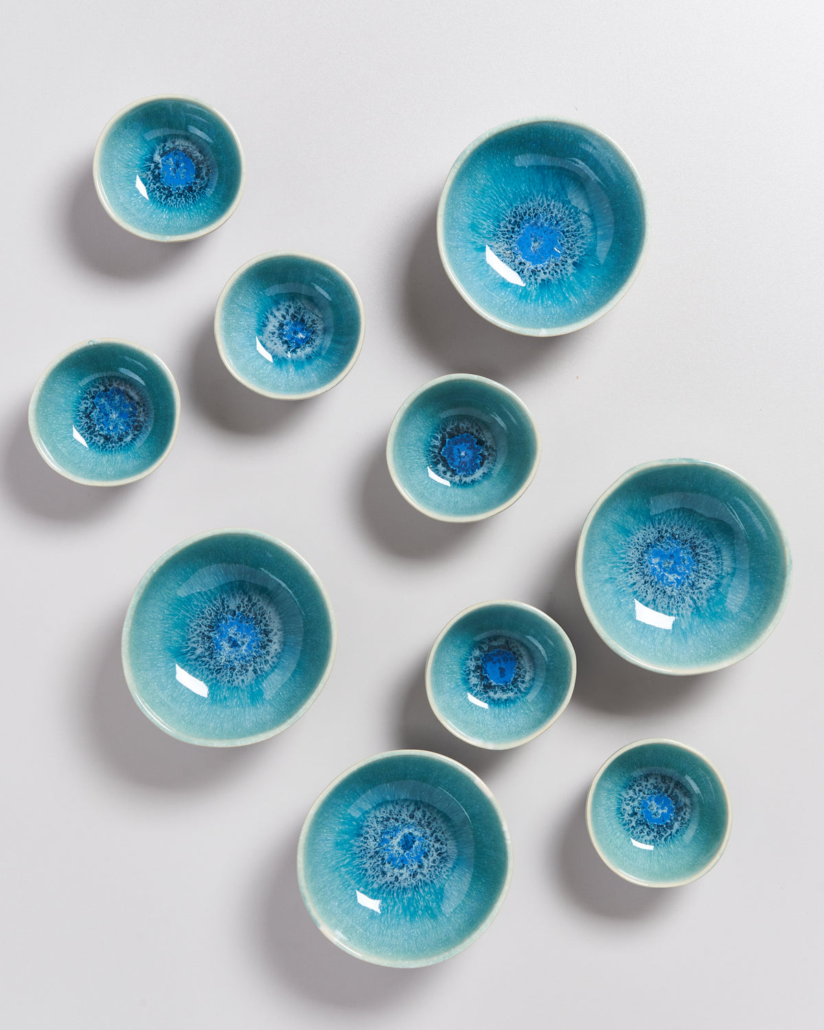 Mehrere blaue Keramikschalen mit intensivem Muster auf einer weißen Fläche verteilt.