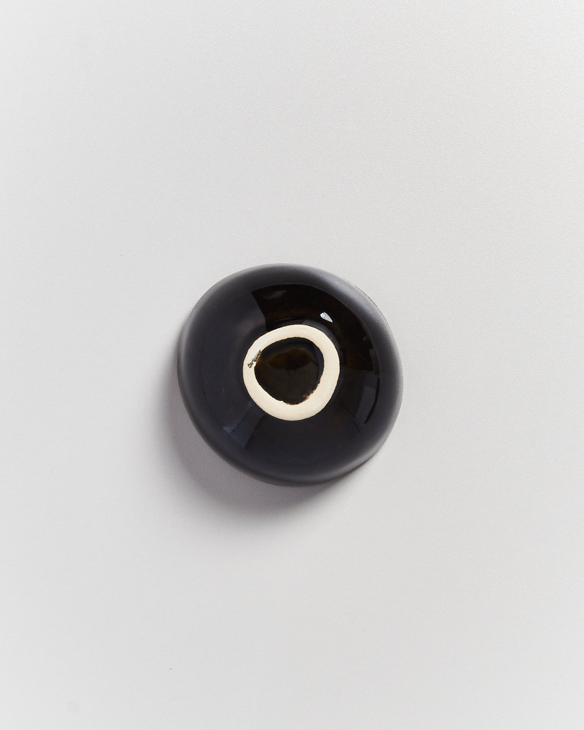 Schwarze Murmel mit weißen Ringen auf grauem Hintergrund.