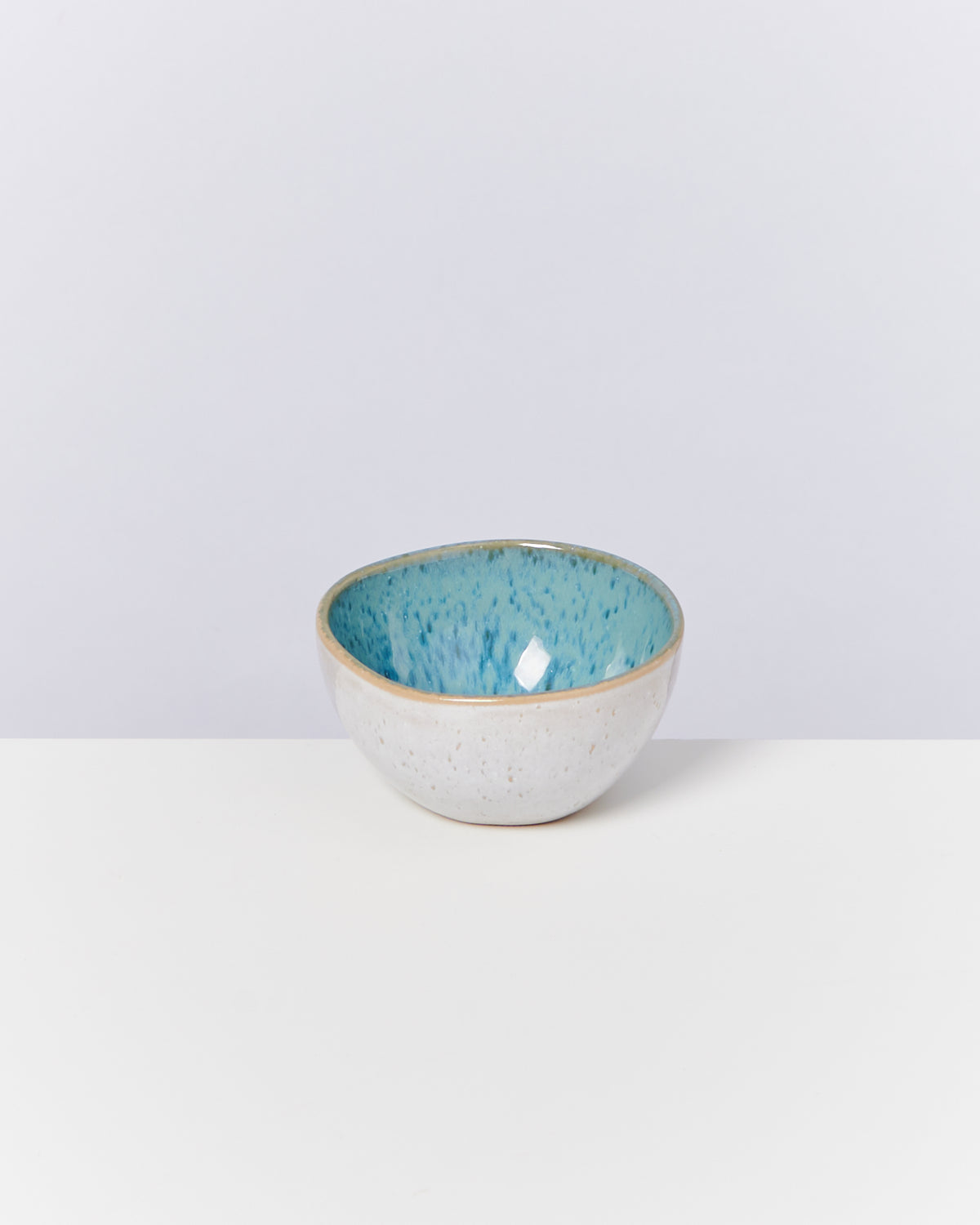 Keramikschale mit blauer Innenseite auf weißem Hintergrund.