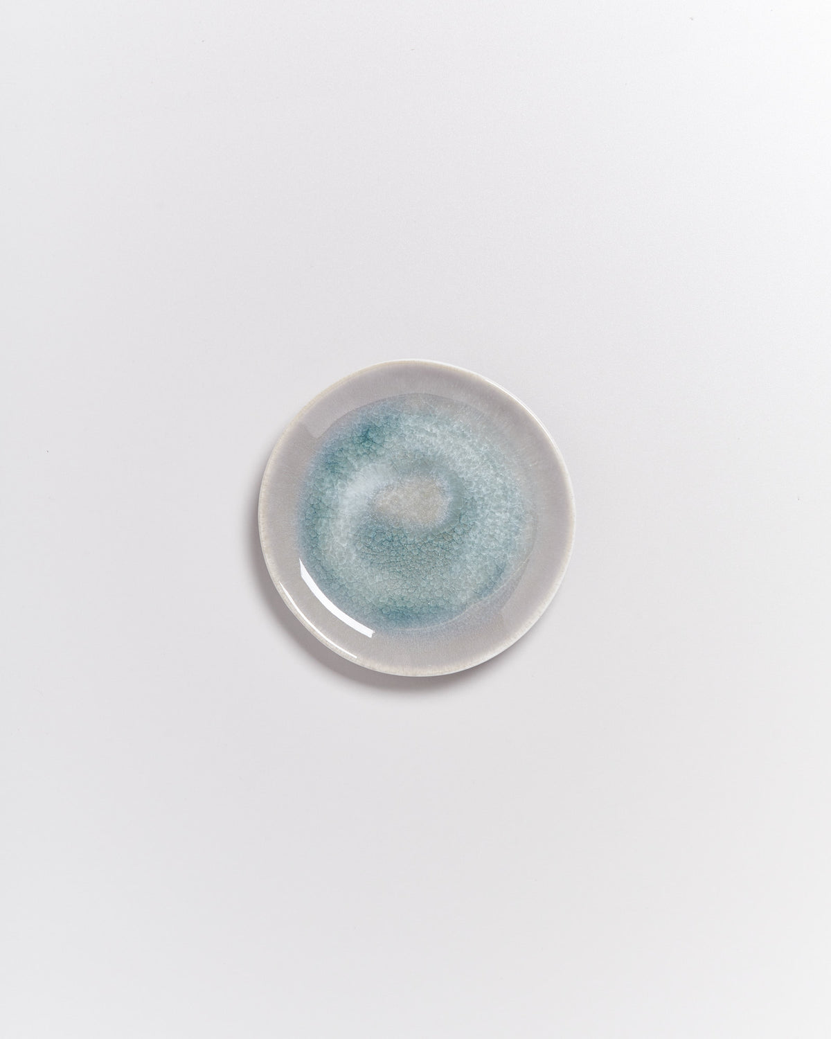 Kleiner Keramikteller mit blau-grüner Glasur auf weißem Hintergrund.