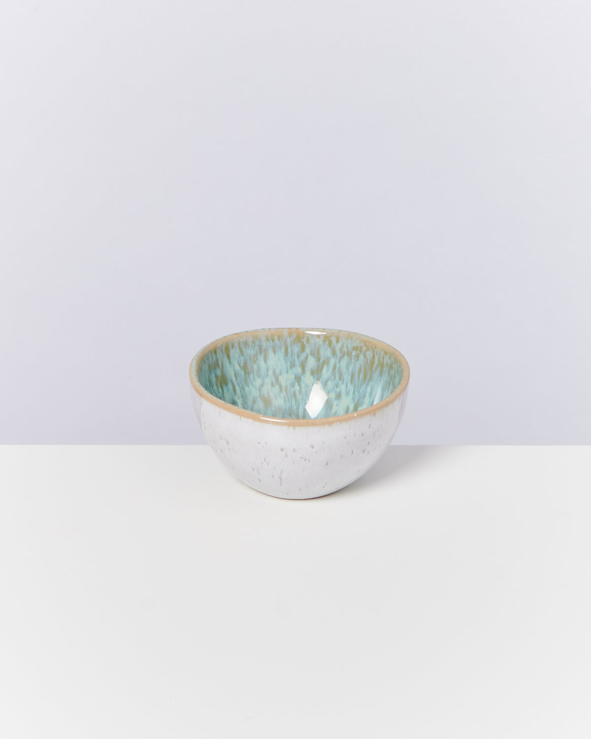 Keramikschale mit weiß-blauer Glasur auf weißem Hintergrund.