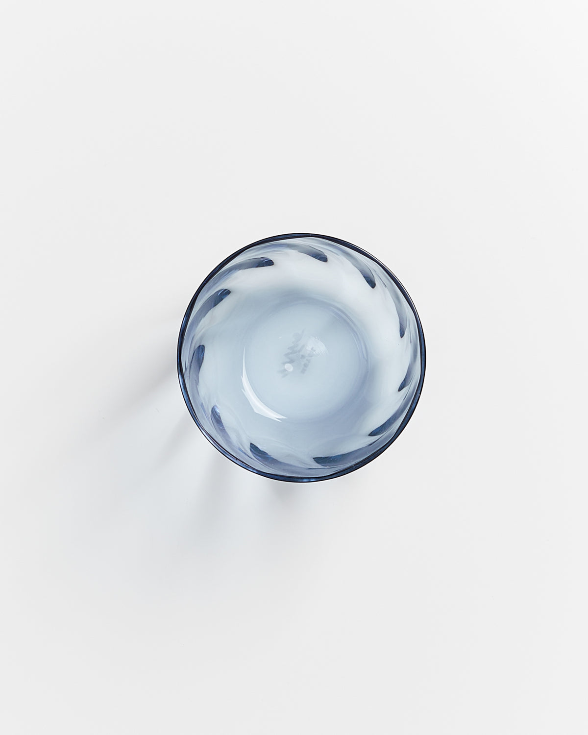 Blaue Glasschale mit weißem Wirbelmuster von oben auf weißem Hintergrund.