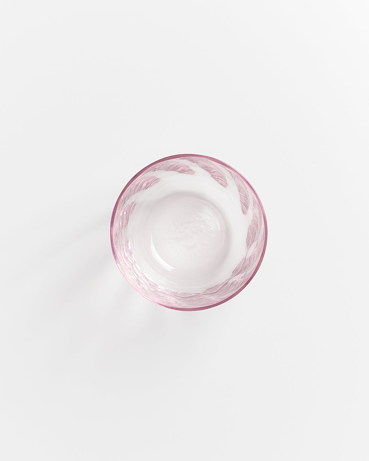 Rosa Glasschale auf weißem Hintergrund, von oben fotografiert.