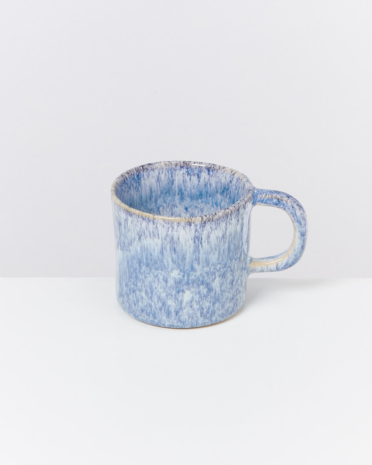 Blaue, gemusterte Keramiktasse mit Henkel auf weißem Hintergrund.
