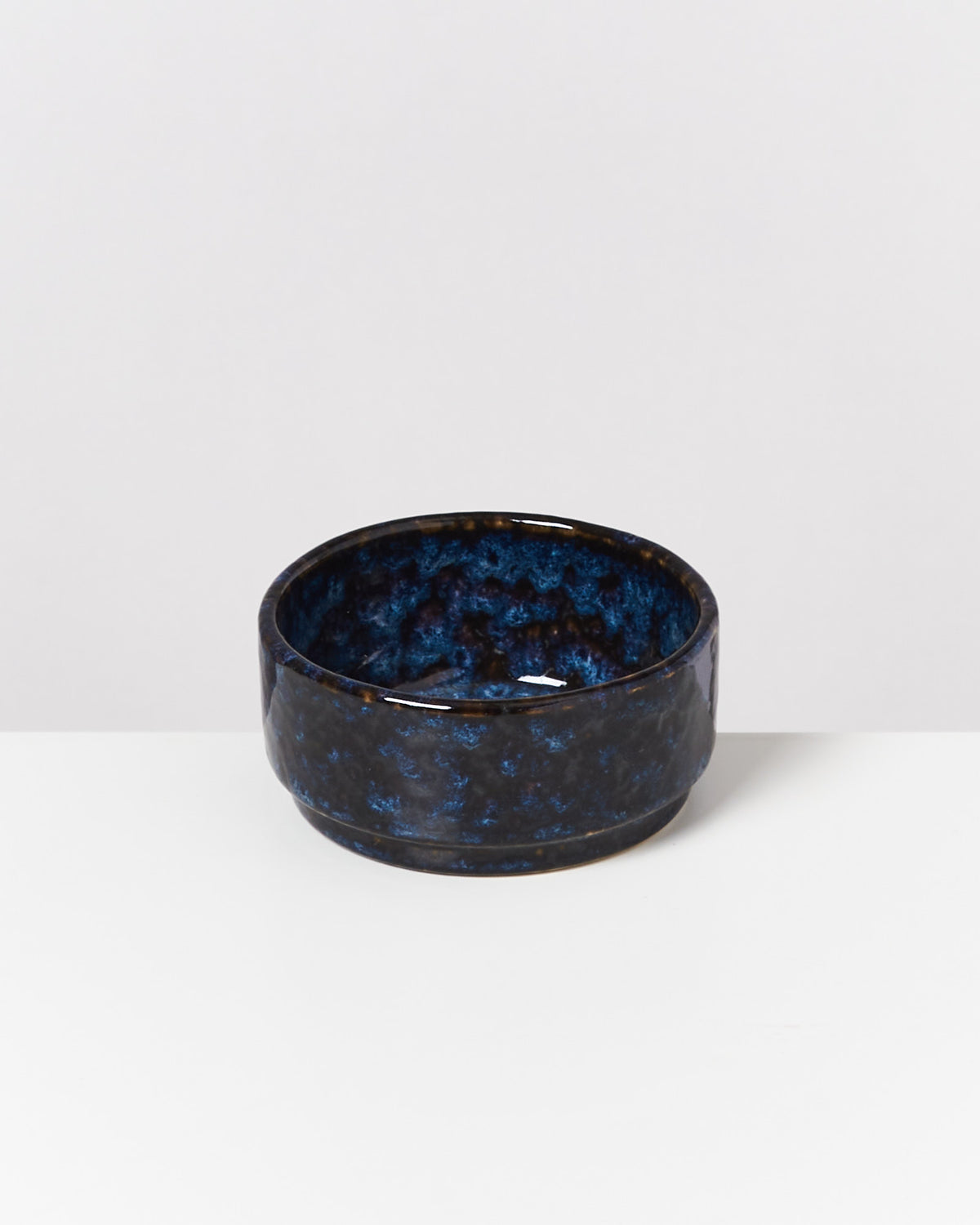 Dunkelblaue, keramikartige Schale mit gemustertem Design auf einem weißen Hintergrund.
