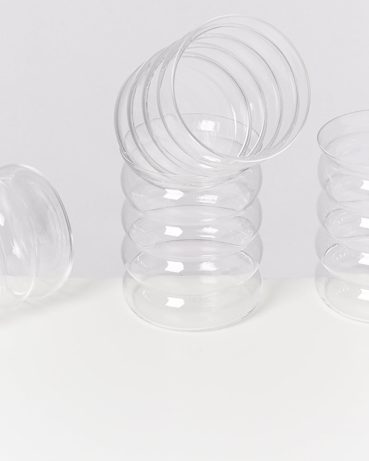 Ein Stapel transparenter, gerippter Gläser auf einer weißen Oberfläche.