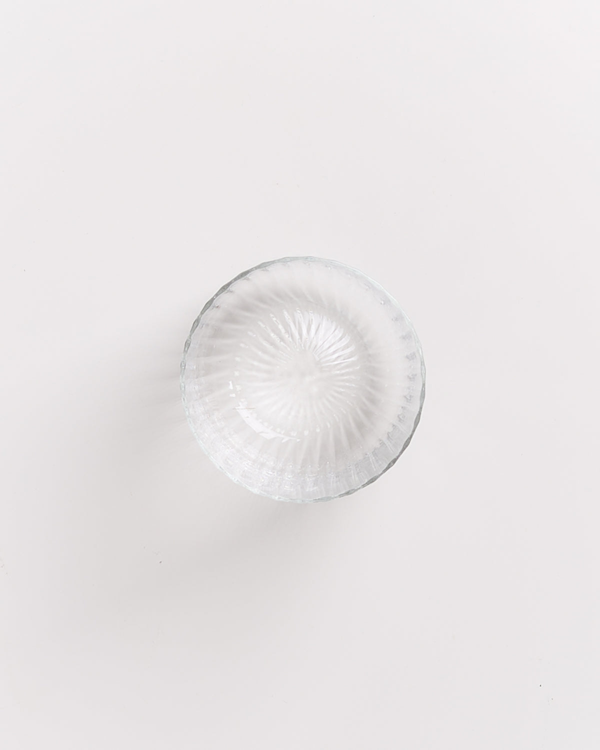 Obenansicht einer leeren, geriffelten Glasschale auf weißem Hintergrund.