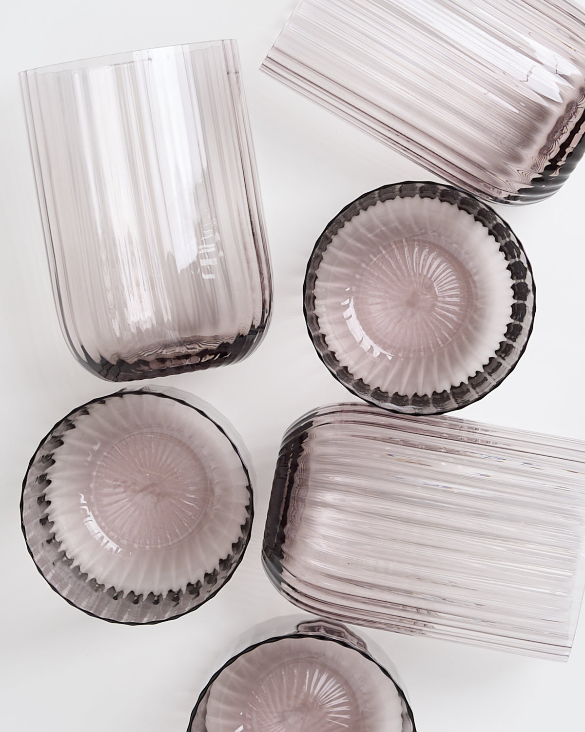 Sechs lilafarbene Glasschalen mit geriffelten Oberflächen auf weißem Hintergrund.