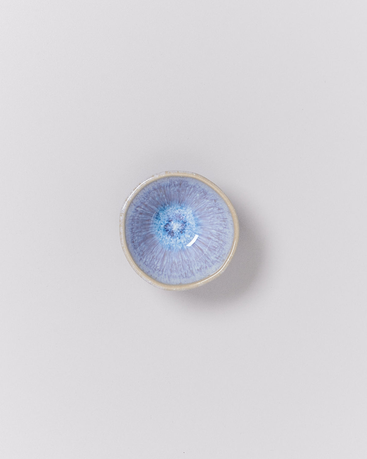 Kleine blaue Keramikschale mit glasiertem Muster auf weißem Hintergrund.