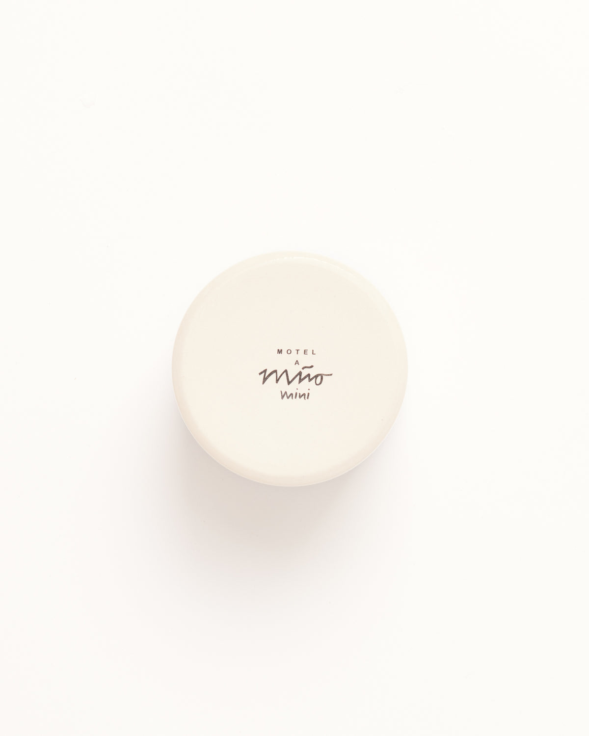 Runder, cremefarbener Keramikbehälterdeckel mit der Aufschrift "Motel a Mio Mini" auf weißem Hintergrund.