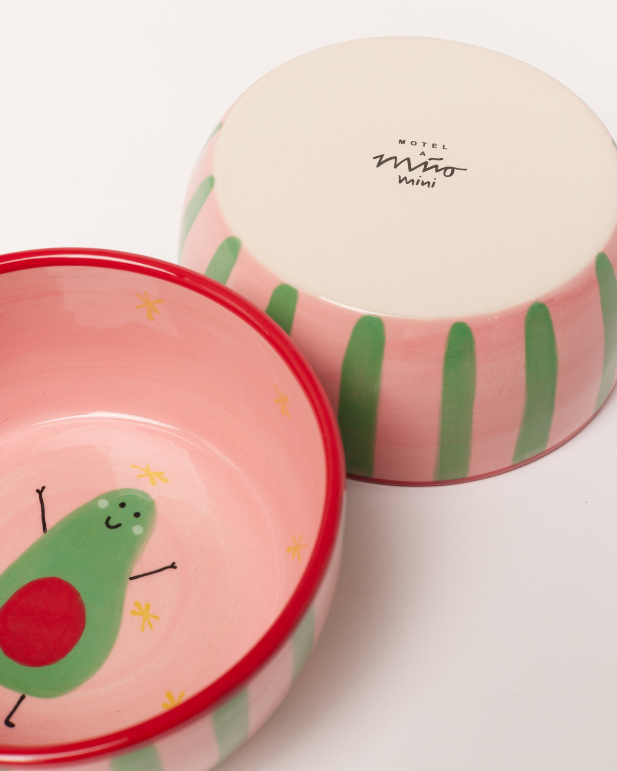 Zwei bunte Schalen, eine mit lachender Avocado und die andere mit grünen Streifen, liegen ineinander.
