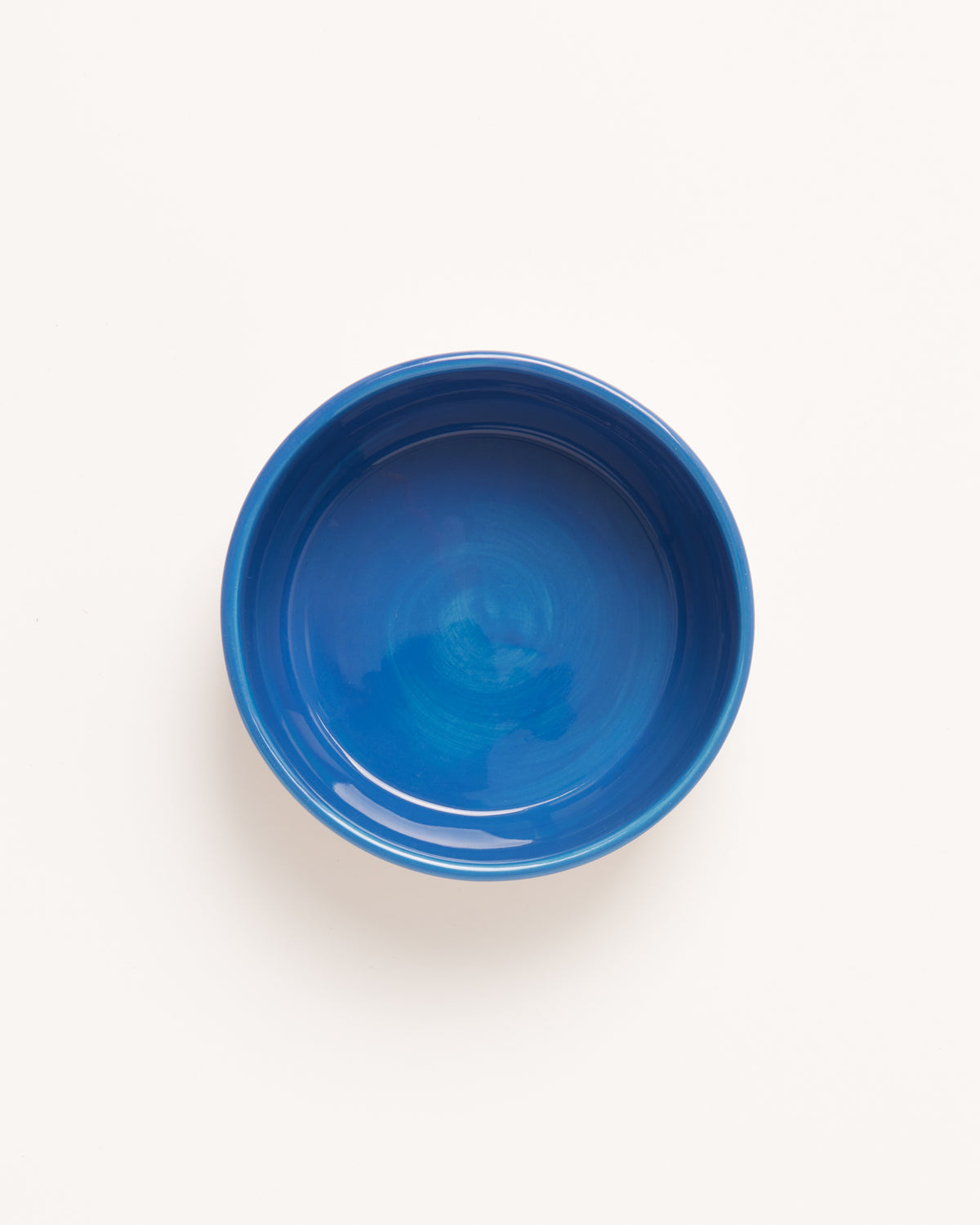 Blaue Keramikschüssel auf weißem Hintergrund, von oben betrachtet.