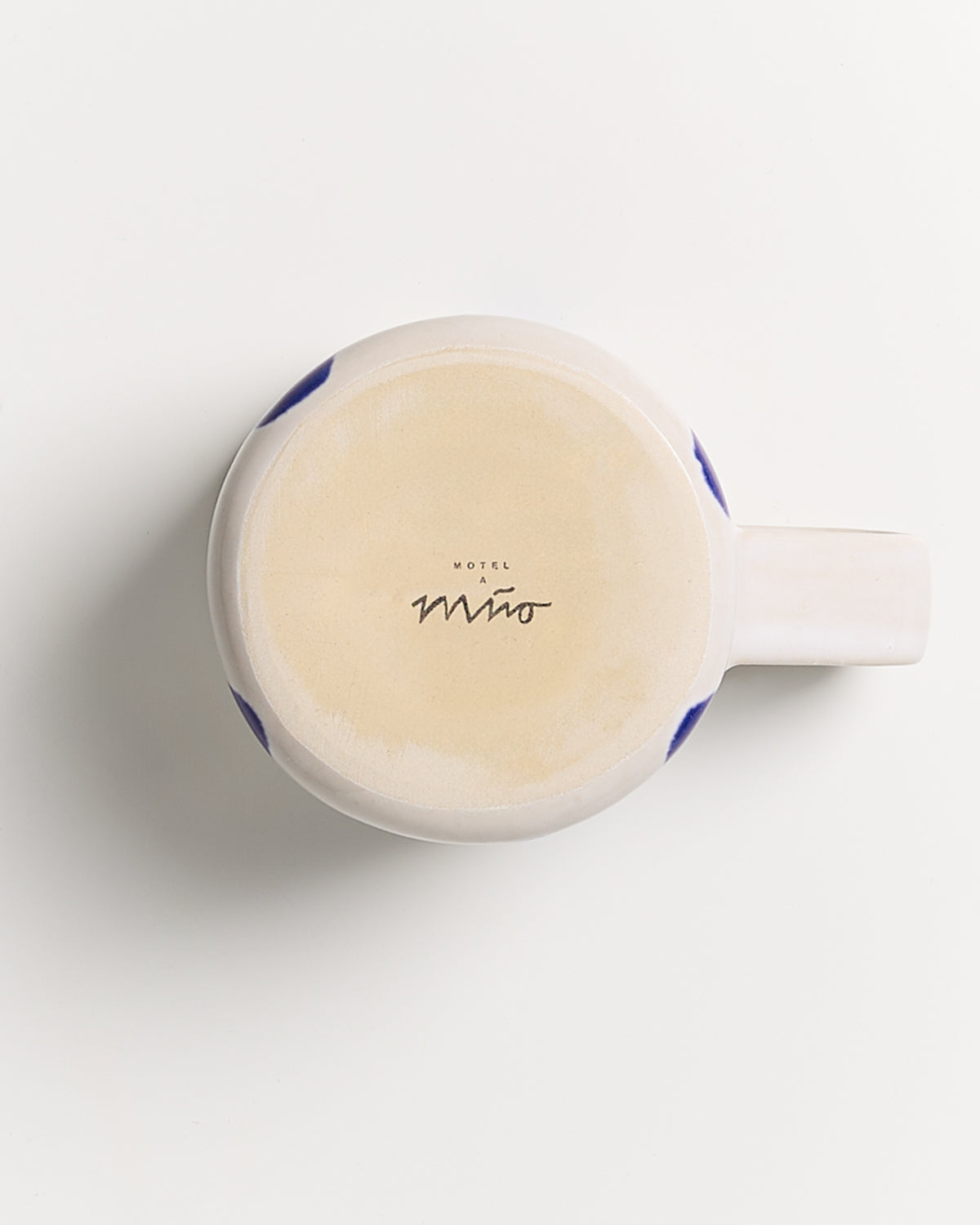 Unterseite einer Tasse mit der Aufschrift "Motel a Miio" auf hellem Hintergrund.