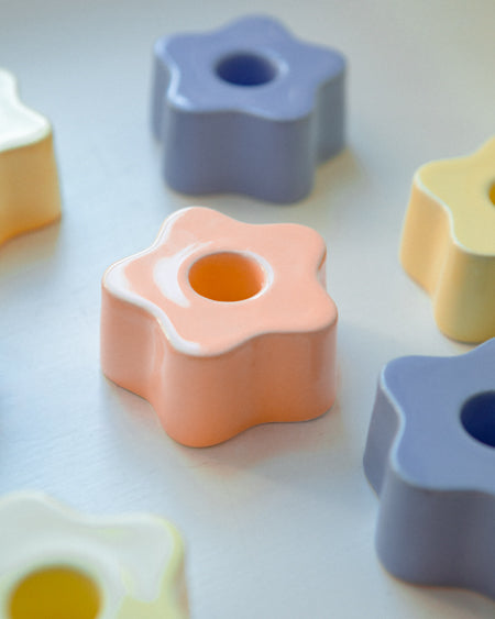 Bunte, sternförmige Kerzenhalter aus Keramik auf einer hellen Oberfläche arrangiert.